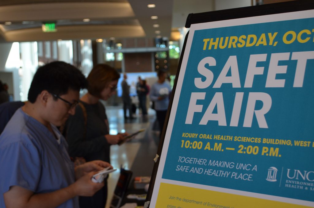 Closeup of Lab Safety Fair poster with attendees in the background