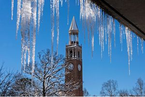 Icicles hanf from a building with the UNC Bell Tower in the background.
