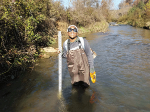 Zay Watkins with measurement tool in a creek.